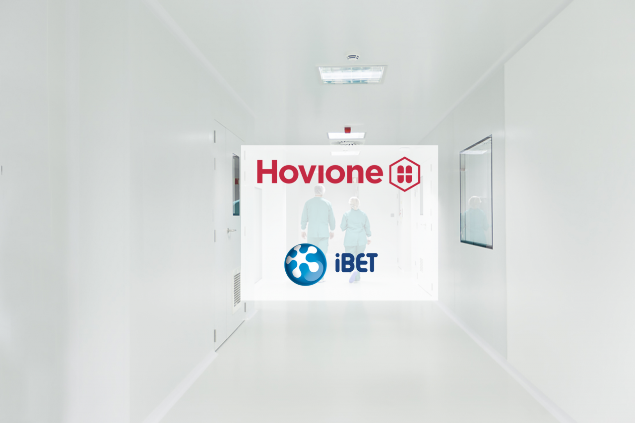 dois operadores caminhar lado a lado num corredor em área de produção com logo da Hovione e do iBET